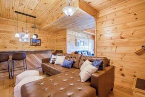 Ein Holzinnenraum mit einer Couch, Sesseln und einer Bar.