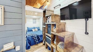Una camera con un letto, scaffali in legno, una televisione e un cartello di benvenuto.