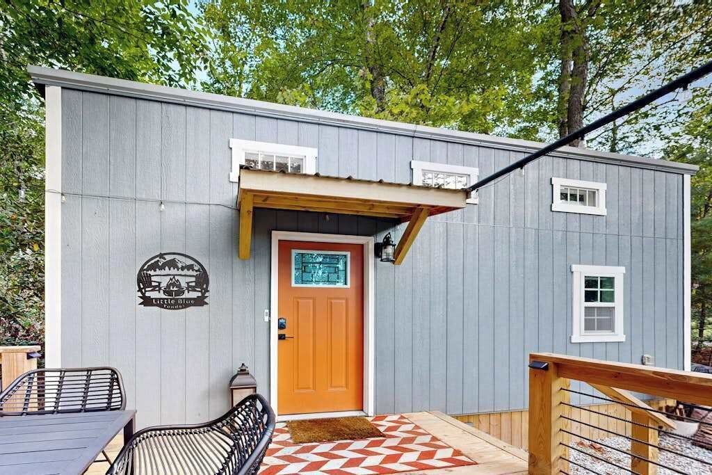 Un petit bâtiment doté d’un porche en bois, d’une porte avec une enseigne et d’une petite fenêtre.