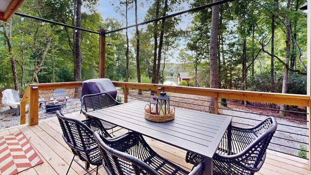 Una terrazza con tavolo e sedie, circondata da alberi.