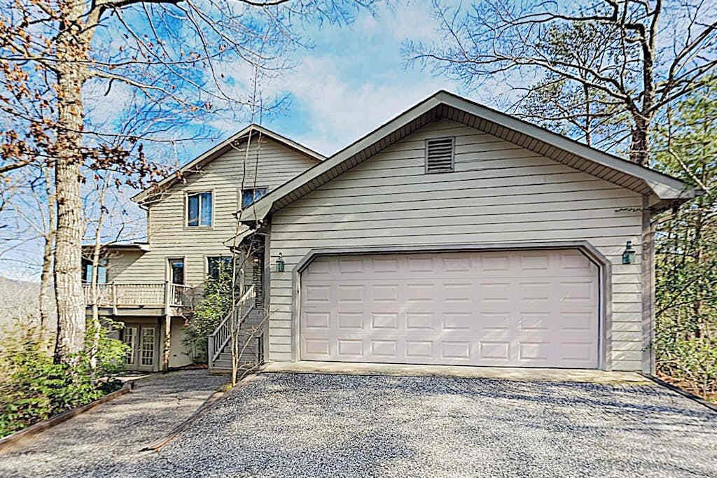 A two-story house with a garage, a staircase leading to the second floor, and a gravel driveway.
