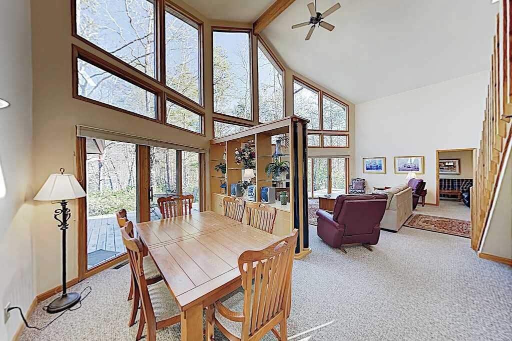 Une pièce spacieuse avec une grande table à manger en bois, plusieurs chaises, un canapé et un ventilateur de plafond.