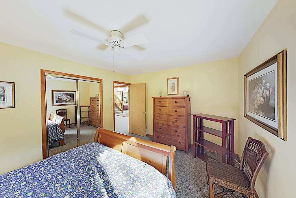 Une chambre à coucher avec un lit, une commode, une chaise et un ventilateur de plafond.