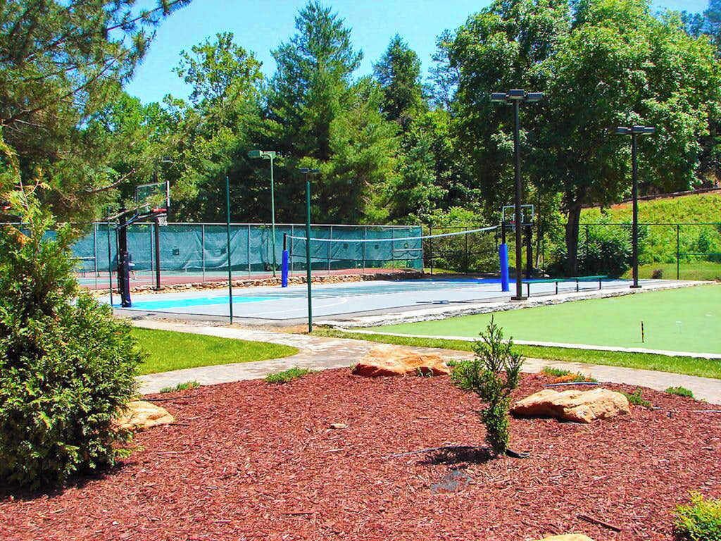Una cancha de tenis con una red, rodeada de árboles y una valla.