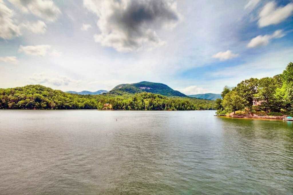 Un lac paisible, avec une colline boisée en arrière-plan.