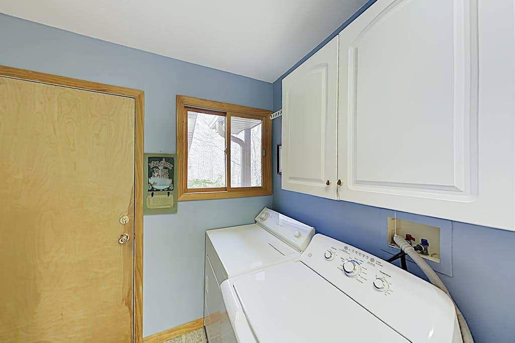 A laundry room with a washer and dryer, a wooden door, and a window.