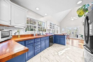 A kitchen with white cabinets, a wooden countertop, and a large island. - Gorgeous chalet perched on a hill with pool and tennis court access (Lake Junaluska)