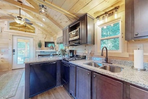 A modern kitchen with granite countertops, stainless steel appliances, and a large window. - Cozy cabin with amazing views, private hot tub, & covered porch. Nearby skiing. (Mars Hill)