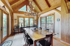 Ein Esszimmer aus Holz mit einem großen Tisch, Stühlen und einer Kandelaber.