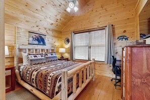 A wooden cabin bedroom with a bed, bedside lamps, a clock, a window with blinds, and a bear-themed wall decoration. - Highlands Water Hideaway (Murphy)