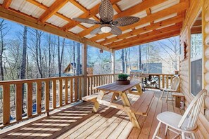 A wooden deck with a table and chairs, a ceiling fan, and a view of trees. - Highlands Water Hideaway (Murphy)