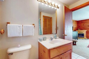 Un bany amb un lavabo, un mirall i dues tovalloles penjades a la paret.
