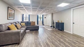 A spacious living room with a sectional sofa, a dark cabinet, and a door.