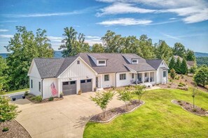 A two-story house with a garage, a covered porch, and a well-maintained lawn. - Mountain & lake-view luxury home with hot tub, deck, & pergola - dog-friendly (Mill Spring)