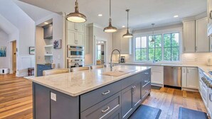 Una cocina moderna con una isla grande, iluminación colgante y vistas al exterior.