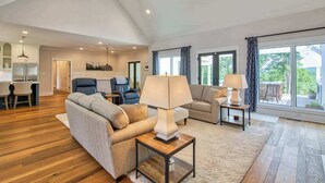 Una sala de estar amplia con un sofá, dos sillones, una mesa de centro y un comedor con mesa y sillas.