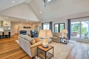 A spacious living room with a sofa, two armchairs, a coffee table, and a dining area with a table and chairs. - Mountain & lake-view luxury home with hot tub, deck, & pergola - dog-friendly (Mill Spring)