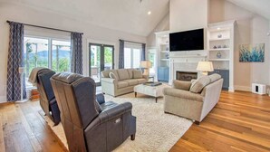 Un salón amplio con chimenea, un televisor de pantalla plana y un ventanal grande con cortinas.