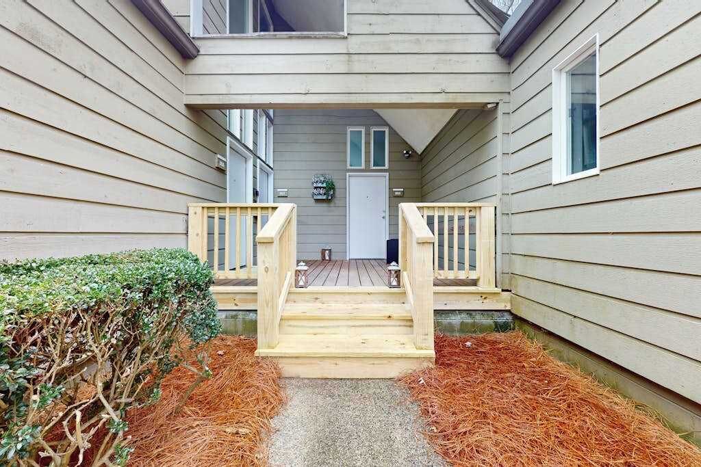 A wooden deck leading to a house with a door and windows.