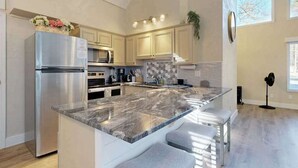 Una cocina moderna con una isla grande, electrodomésticos de acero inoxidable y armarios de colores claros.
