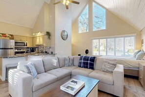 Eine moderne Küche mit Edelstahlgeräten, einem Essbereich mit Holztisch und einem großen Fenster, das natürliches Licht hereinlässt.