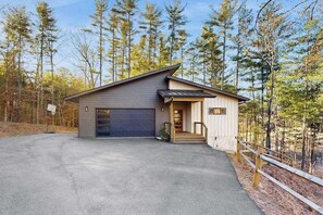Ein Bungalow mit Garage, Veranda und Auffahrt.