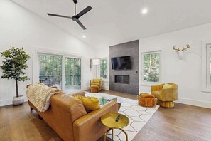 Ein modernes Wohnzimmer mit einer Couch, gelben Sesseln, einem Fernseher und einem Kamin.