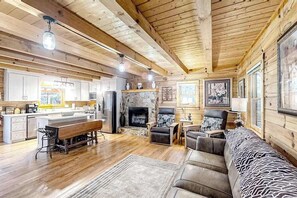 Ein Holzblockhaus-Interieur mit Küche, Essbereich, Kamin und Sitzgelegenheiten.