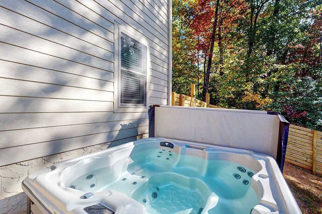 Een hottub in een achtertuin met een houten schutting en bomen.