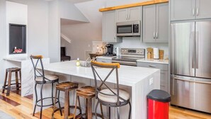 A modern kitchen with grey cabinets, stainless steel appliances, and a white island with bar stools. - Idyllic home with 2 separate apartments near skiing/hiking - firepit, fast WiFi (Swannanoa)