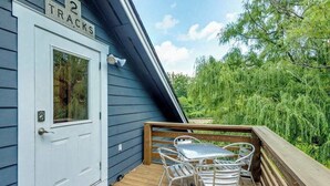 A wooden deck with a white door labeled '2 TRACKS,' a metal table with chairs, and a view of greenery. - Idyllic home with 2 separate apartments near skiing/hiking - firepit, fast WiFi (Swannanoa)