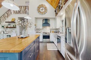 A modern kitchen with a central island, stainless steel appliances, and a decorative clock on the wall. - Rustic Lake Lure retreat with wifi, custom charm, lake fun & mountain views (Lake Lure)