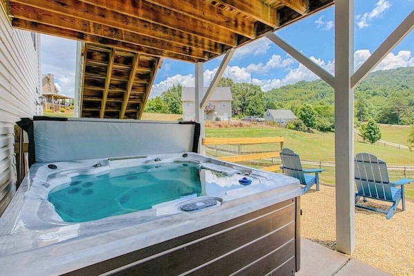Un jacuzzi bajo una pérgola de madera con vistas a un paisaje cubierto de césped y casas.
