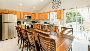 A modern kitchen with wooden cabinets, stainless steel appliances, and a large dining table. - Blue Ridge farmhouse with amazing mountain view, hot tub, firepit & decks (Weaverville)
