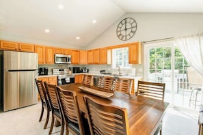 Una cocina moderna con armarios de madera, electrodomésticos de acero inoxidable y una amplia mesa de comedor.