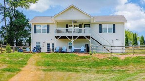 A two-story house with a balcony, a front porch, and a fenced yard. - Blue Ridge farmhouse with amazing mountain view, hot tub, firepit & decks (Weaverville)