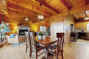 Ein Holzblockhaus-Interieur mit Essbereich, Kamin und Küche.