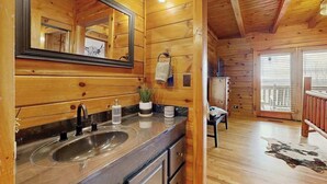 Interior de una cabaña de madera con un espejo grande, un lavamanos y una silla.