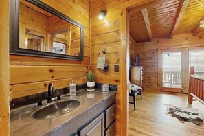 Ein Holzblockhaus-Innenraum mit einem großen Spiegel, einem Waschbecken und einem Stuhl.