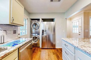 Une cuisine équipée d’un réfrigérateur en acier inoxydable, d’un lave-linge et d’un sèche-linge intégrés, et d’un plan de travail en marbre.
