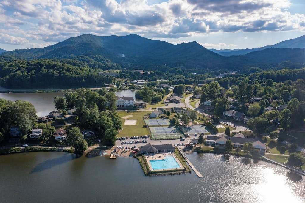 Vista aérea de um resort à beira de um lago, com piscina, quadras de tênis e um clube.