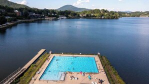 En swimmingpool med utsikt över en sjö och berg i bakgrunden.