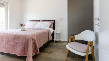 A bedroom with a bed, bedside table, chair, and a door.