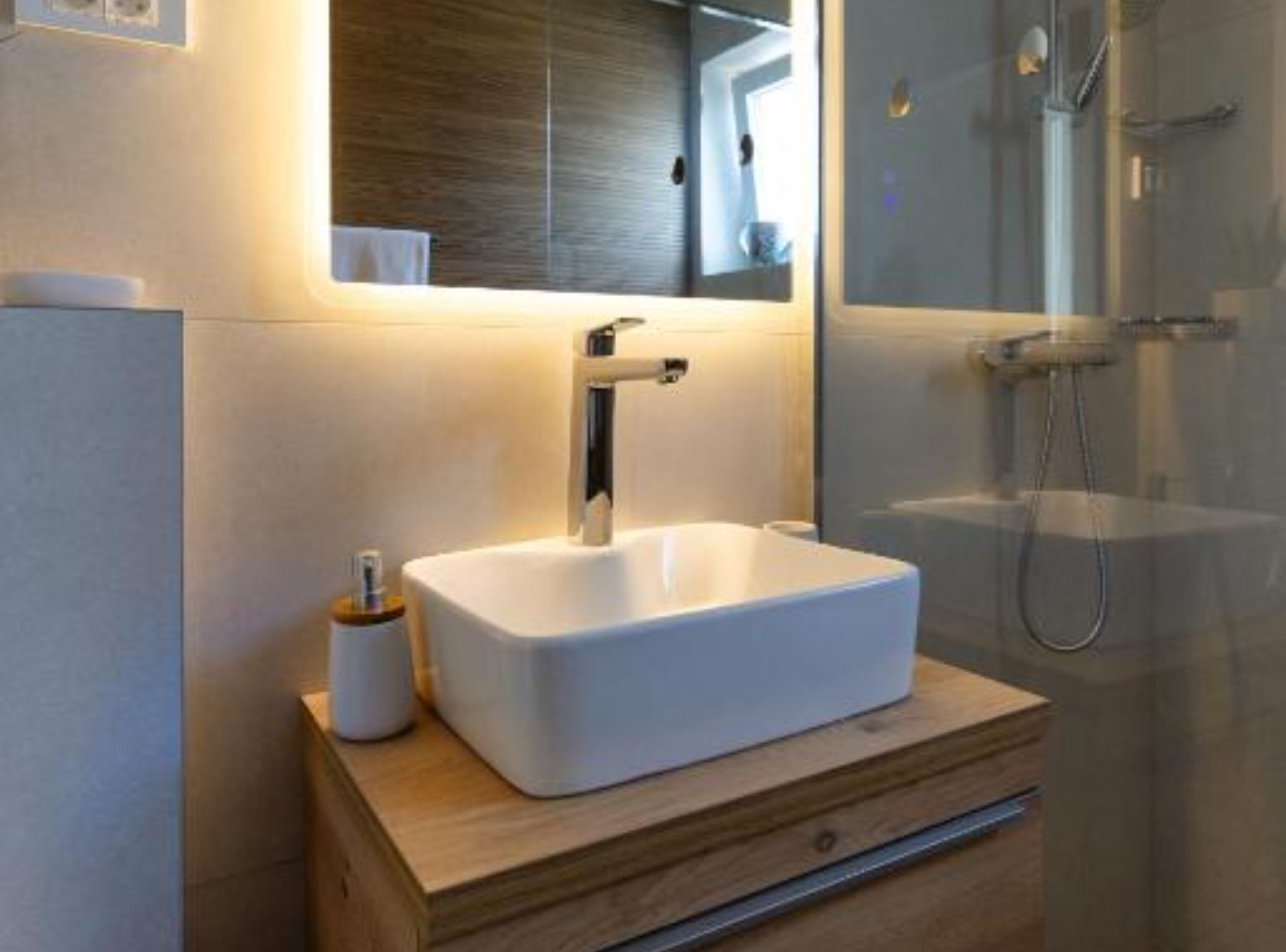 Une salle de bain moderne avec un lavabo blanc, un miroir et une douche.