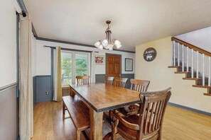 A dining room with a wooden table and chairs, a chandelier, and a staircase. - Charming Riverfront House with Full Kitchen, Wifi, and Central AC | Dog-Friendly (Marshall)