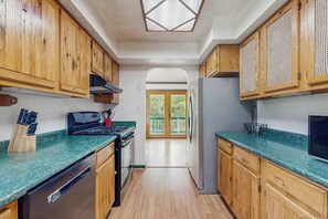 A kitchen with wooden cabinets, a stainless steel refrigerator, and a green countertop. - Charming Riverfront House with Full Kitchen, Wifi, and Central AC | Dog-Friendly (Marshall)