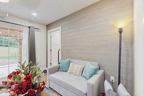 A living room with a grey sofa, a lamp, and a window with curtains.