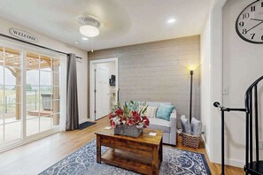 A living room with a sofa, a coffee table with a flower arrangement, a clock, and a staircase.