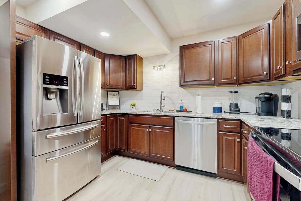 A modern kitchen with stainless steel appliances, wooden cabinets, and a white countertop.