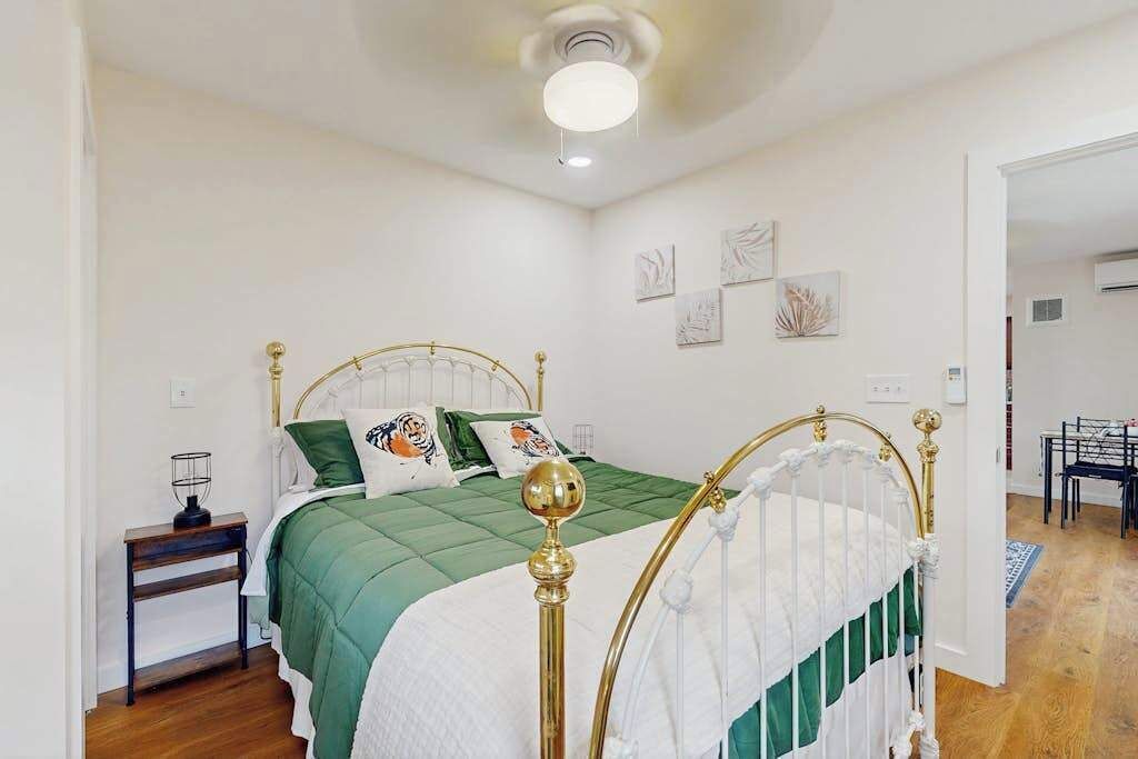 A bedroom with a bed, a nightstand, a chair, and a door leading to another room.